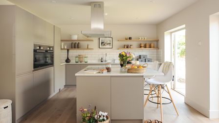 Modern gray kitchen with sleek kitchen island, bar stools, metro tiling and built-in cupboards with built-in oven